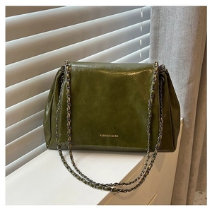 Detail of dark green leather tote bag with fashion lettering and dual metal chain straps