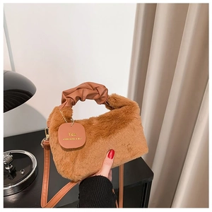 Detailed close-up of brown plush faux fur handbag with ruched handle and brand tag