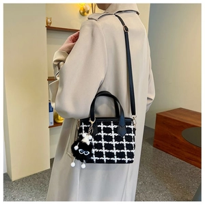 Detail of tweed bucket bag with black and white check pattern and plush charm accessory