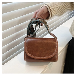 Detailed view of a brown vintage crossbody bag featuring a floral patterned wide strap