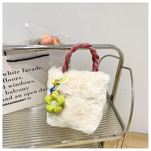 Détails d'un sac seau en peluche blanche avec poignée tressée rose et breloque fleurie