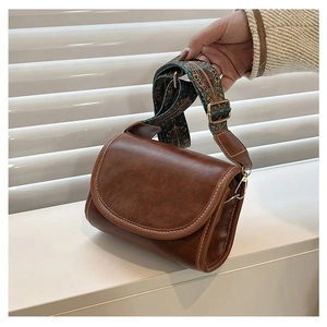 Detail of vintage brown leather crossbody bag with ethnic embroidered wide shoulder strap