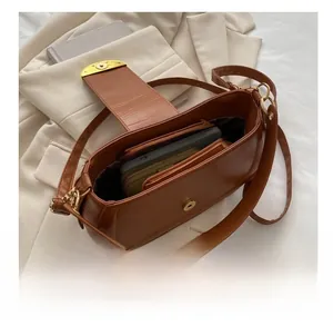 Intérieur spacieux d'un sacoche en cuir marron montrant le rangement du téléphone et du portefeuille