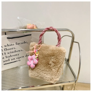 Détail d'un sac seau en fausse fourrure pelucheuse avec anse rose et breloque fleurie