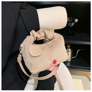 Detail of beige plush handbag with ruched handle and leather strap shown on dark coat