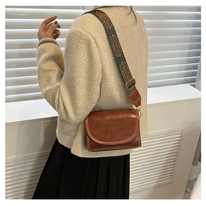 Brown vintage leather shoulder bag with ethnic patterned wide strap on a model