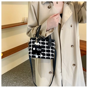 Detail of tweed bucket bag with checkerboard pattern and plush eyeball charm on model