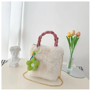 Détail du sac seau en fausse fourrure blanche avec anse tissée rose et breloque marguerite