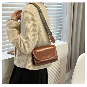 Brown vintage flap crossbody bag featuring a decorative ethnic style wide shoulder strap