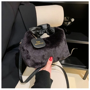 Detail of soft black faux fur handbag featuring pleated leather handle and branded tag