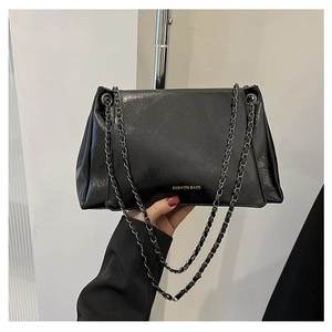 Detail of glossy black patent leather surface with gold Fashion Bags lettering and chain