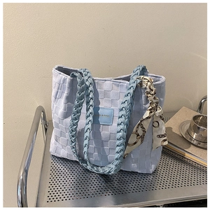 Detail of light blue quilted tote bag featuring a decorative silk scarf and fashion logo