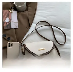Detail view of contrast color crossbody bag with gold metal buckle on white fabric