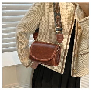 Detail of caramel vintage shoulder bag with white stitching and boho patterned wide strap