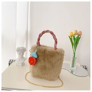 Détail d'un sac seau en peluche marron avec anse tressée rose et breloque fraise