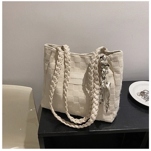 Detail of a beige woven tote bag with a patterned scarf and a leather fashion logo