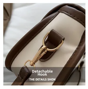 Detail of detachable gold hook and stitching on brown and beige crossbody bag
