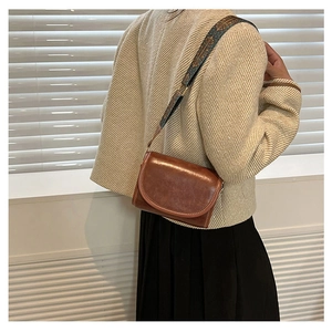 Detail of vintage brown crossbody bag with embroidered floral strap shown on model