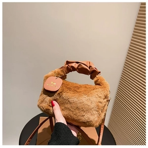 Detail of soft brown plush handbag with wrinkled leather handle and brand tag