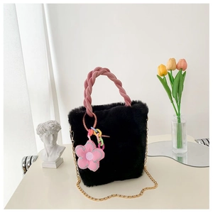 Détail du sac seau en fausse fourrure noire avec poignée tressée rose et pendentif fleur