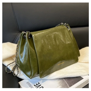 Detail of dark green oily leather tote with metal chain strap and flap closure