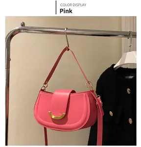 Sacoche selle rose en cuir avec boucle en croissant doré sur un support d'étalage