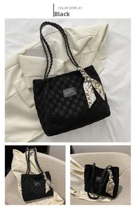 Detail of black checkered tote bag featuring a decorative silk scarf and woven shoulder strap