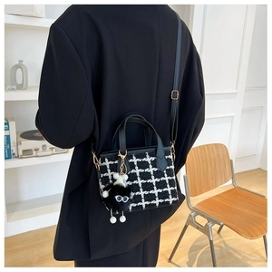 Detail of tweed bucket bag with black and white plaid and a playful plush toy charm