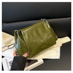 Detailed view of olive green leather bag featuring a fashion logo and metal chain strap