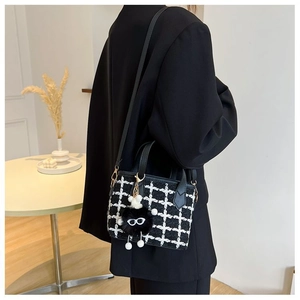 Close-up of black and white tweed bucket bag with monster charm on model