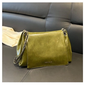 Close-up of olive green glossy faux leather bag with metal chain strap and fine texture