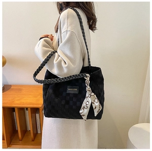 Detail of black checkered tote bag with woven straps and decorative silk scarf detail