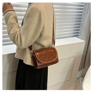 Detail view of a vintage brown PU leather crossbody bag with white contrast stitching