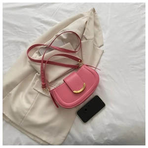 Vue détaillée du sac besace rose avec boucle dorée en croissant sur blazer chic