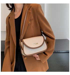 Detail of a two-tone PU leather crossbody bag with a gold buckle and brown trim