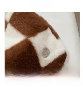 Gros plan du sac cabas en peluche à damier marron et blanc avec emblème métallique