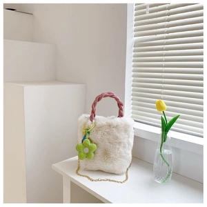Détail du sac seau en fausse fourrure crème avec poignée tissée rose et breloque fleur