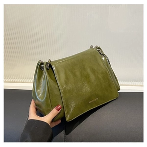 Detail of olive green oil-wax leather texture and metal chain strap on tote bag