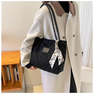 Detail of black woven tote bag featuring decorative silk scarf and leather logo patch