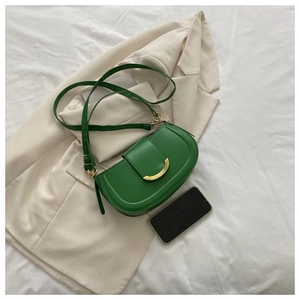 Détail d'un sac besace en cuir vert vif avec une boucle décorative en métal doré