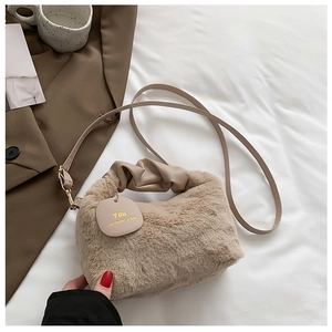 Detail of plush beige faux fur handbag featuring soft cloud-shaped handle and metal logo