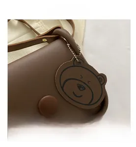 Close-up of brown leather crossbody bag featuring magnetic clasp and bear charm