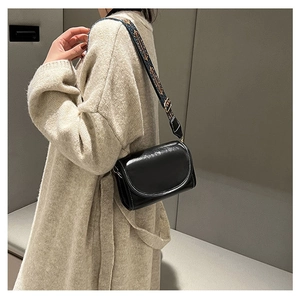 Detailed view of black leather crossbody bag with bohemian embroidered wide strap