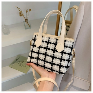 Detail of tweed bucket bag showing black and white texture with cream leather handle