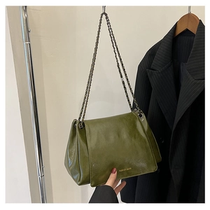Detail of olive green glossy leather shoulder bag with vintage chain and fashion logo