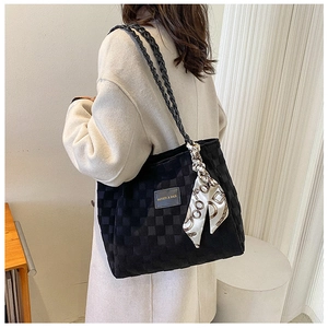 Detail of black quilted tote bag with silk scarf accent and woven straps on model