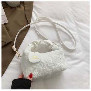 Detail of white plush handbag featuring a pleated cloud handle and golden brand plaque