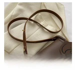 Close-up of brown faux leather shoulder strap with gold buckle and bear charm decoration