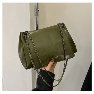 Detailed close-up of olive green glossy faux leather tote bag with woven chain strap