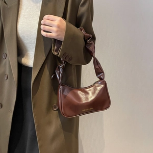 Brown glossy leather baguette bag with pleated shoulder strap and gold lettering